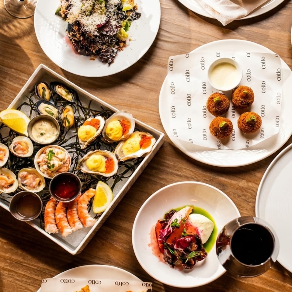 A wooden table laden with various Italian dishes, including seafood, pasta, and meat entrees.
